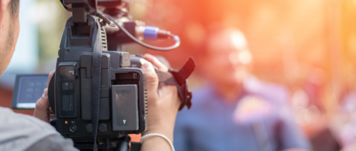 cameraman holding a camera to record a journalist